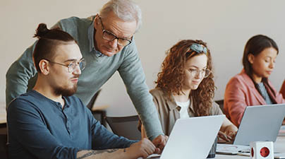 instructor supporting a member of a class working on a computer